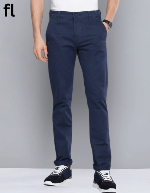 A man standing against a grey background, wearing navy cotton imported stuff pants with a smart fit.